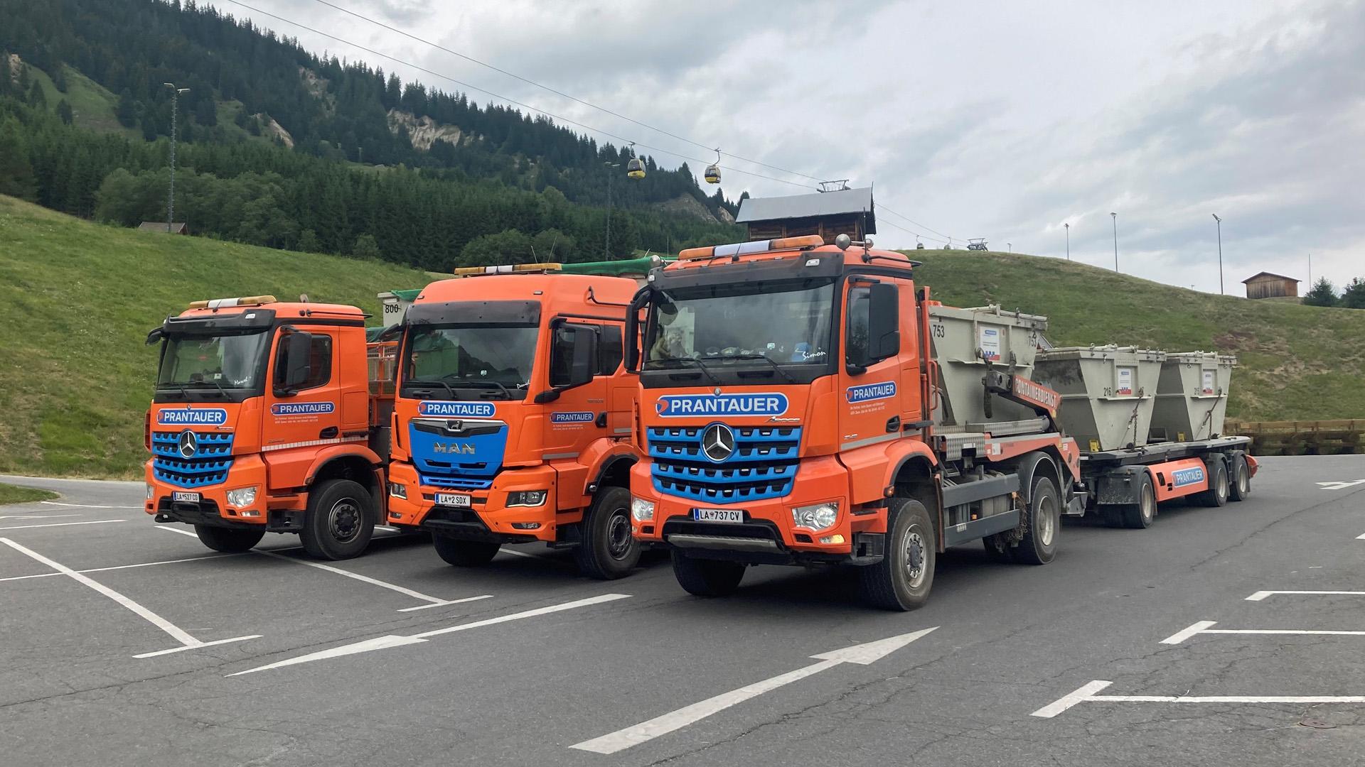 Zwei Absetz- und ein Abrollkipper mit Hänger und Containern beladen auf einem Parkplatz