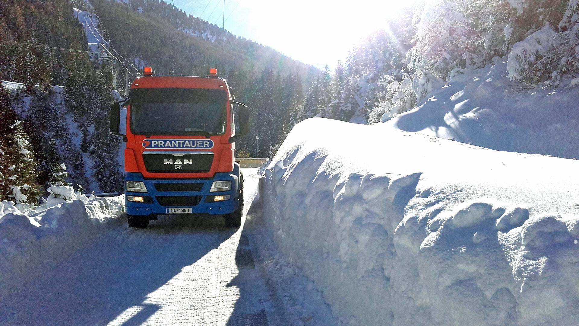 LKW auf Schneefahrbahn und Schneewand auf der rechten Fahrbahnseite