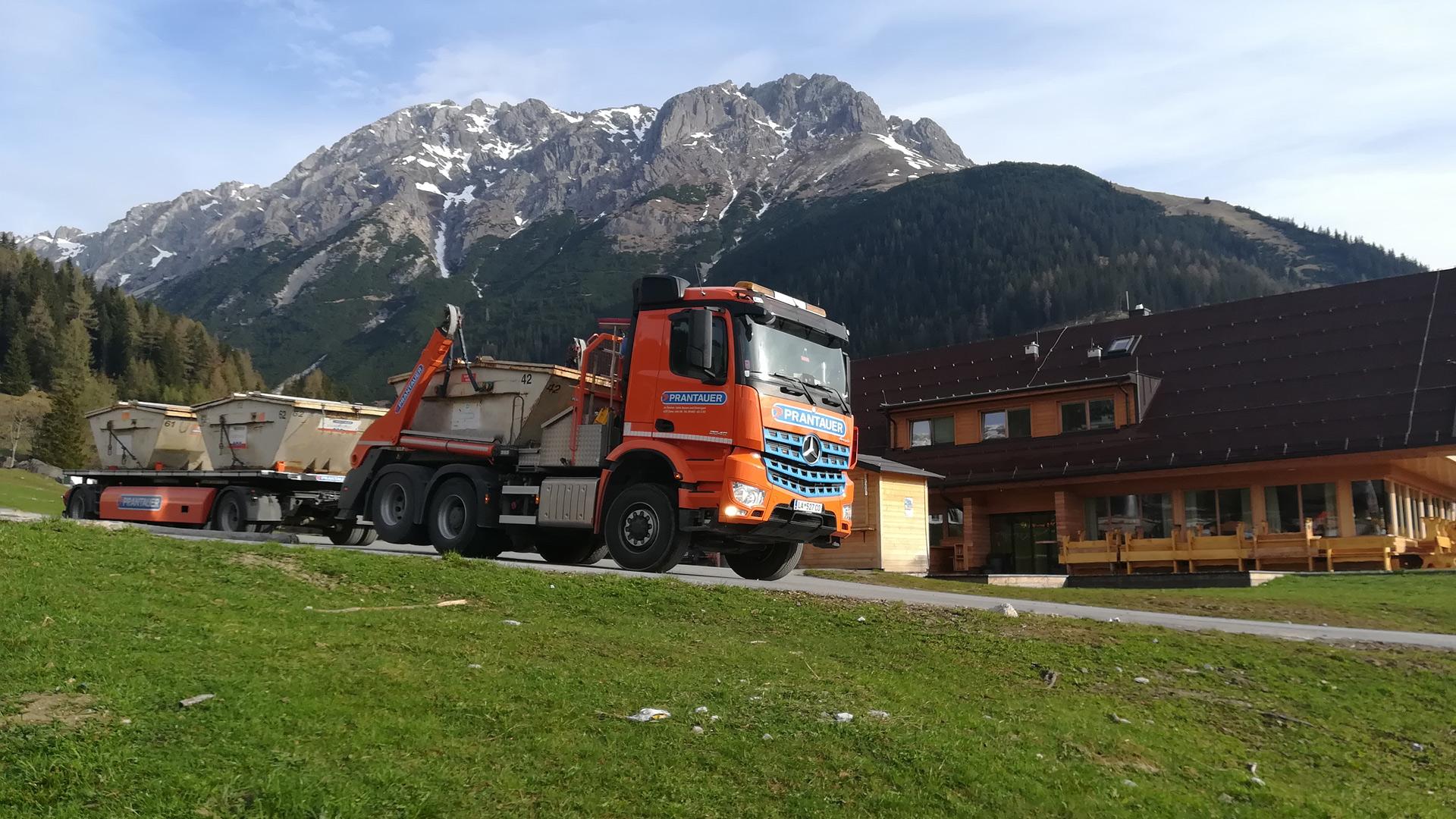 Absetzkipper mit Hänger und Container beladen, im Hintergrund die Untermarkteralm und die Platteinspitze